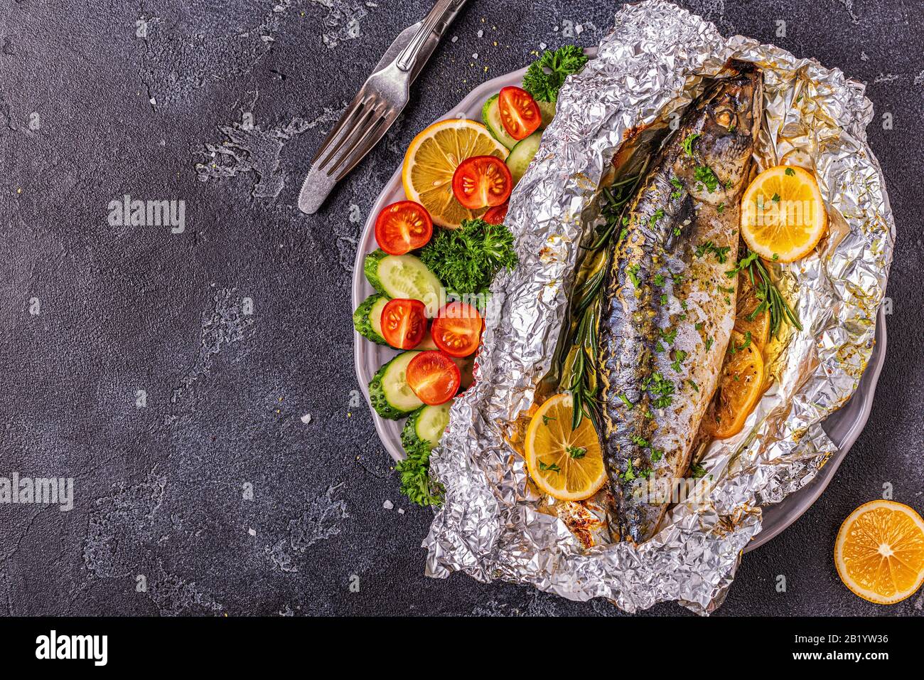 Mackerel baked in foil with vegetables on a dish, top view Stock Photo