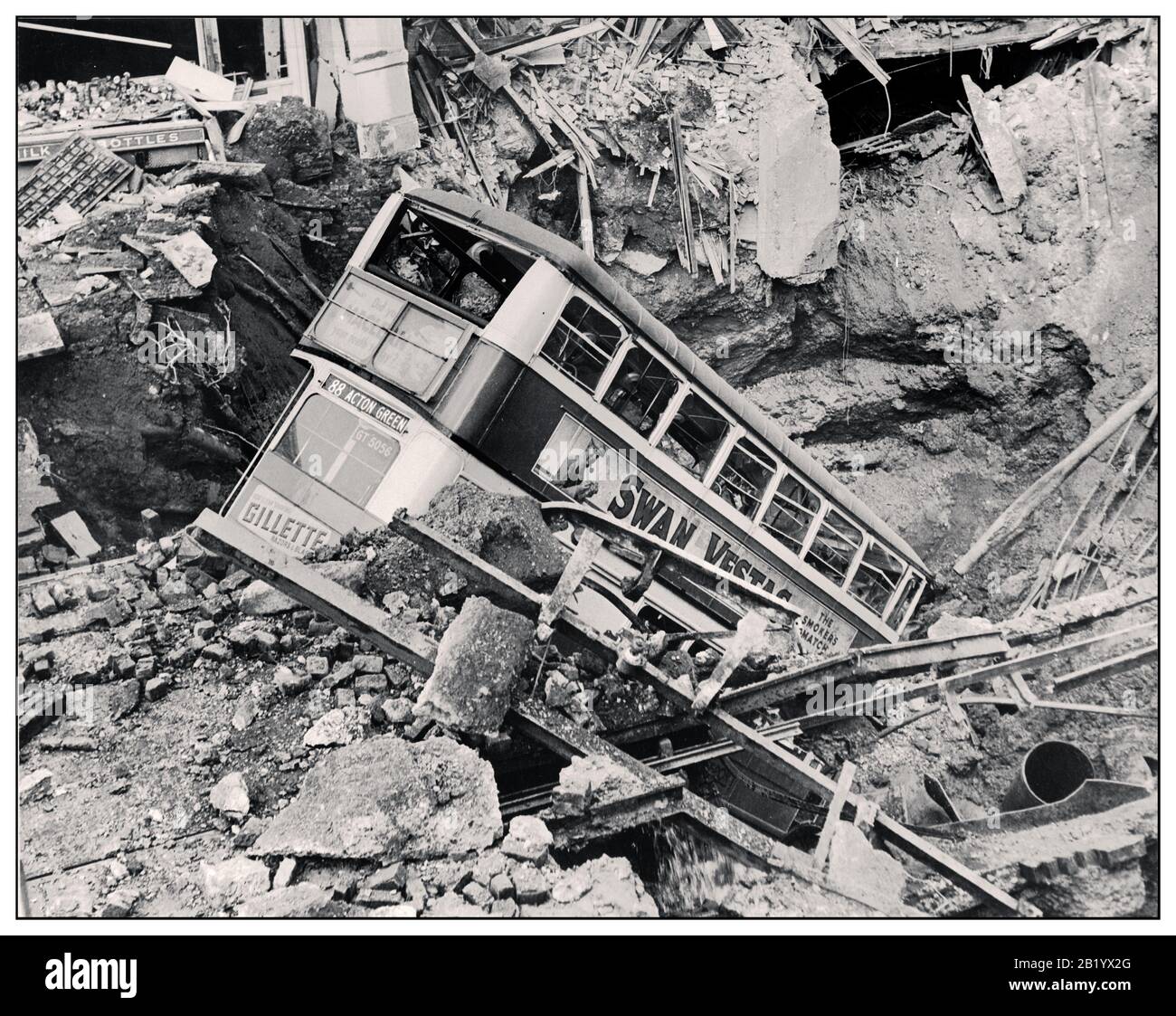 THE LONDON BLITZ BUS BOMB CRATER WW2 1940’s Nazi Air Raid Bomb Damage in Britain during the Second World War In the aftermath of a bombing raid, a London bus lies in a bomb crater in Balham, South London. World War II Stock Photo