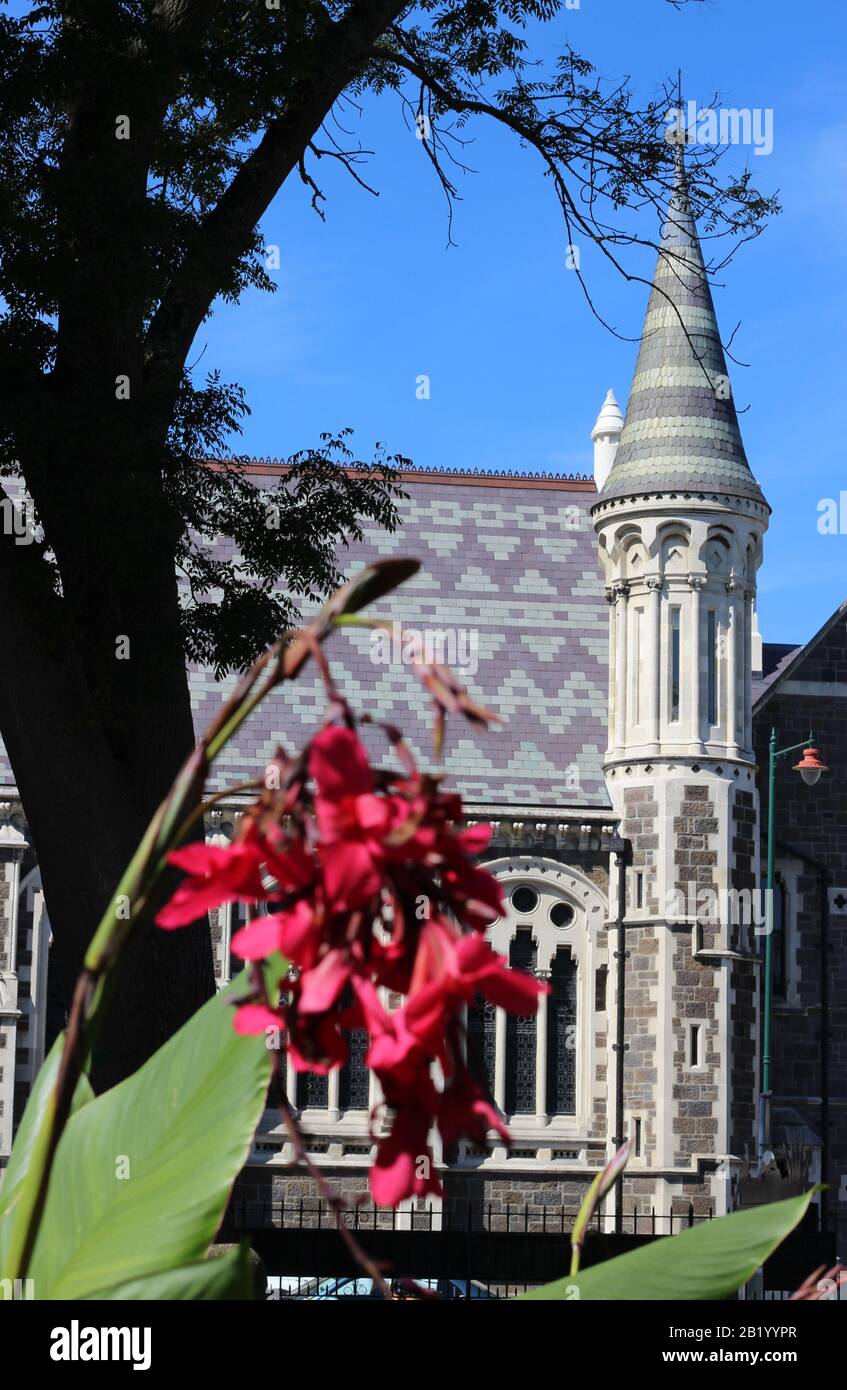The Arts Centre Te Matatiki Toi Ora, Christchurch, New Zealand. The turret is framed by trees and flowers from the neighbouring Botanic Gardens Stock Photo