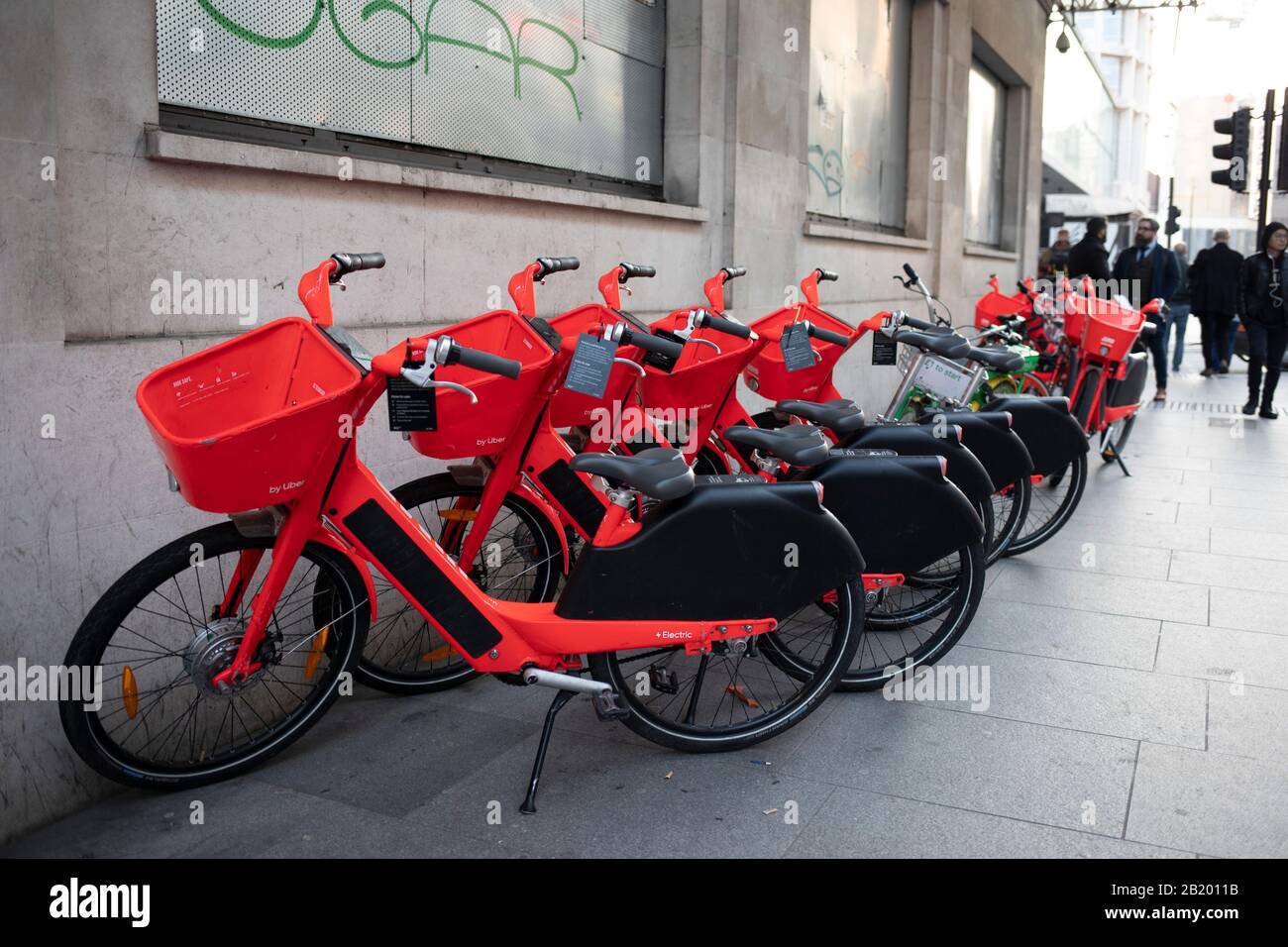Row of standing Jump dockless bike sharing electric cycles on 21st January 2020 in London, England, United Kingdom. Social Bicycles Inc., doing business as Jump, is a dockless scooter and electric bicycle sharing system operating in the United States, Germany, Portugal and the United Kingdom. The bikes are a bright red orange. They can be located using the Jump or Uber apps, and users are charged to their Uber account. Stock Photo