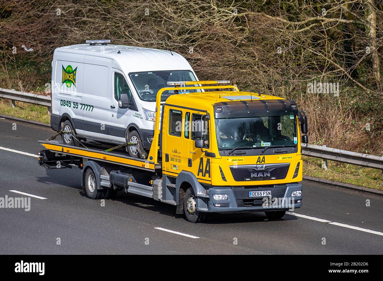 AA Van yellow recovery truck carrying broken down van; Side view of MAN rescue breakdown 24hr recovery vehicle transporting commercial vehicle on M6, Lancaster, UK; Vehicular traffic, transport, modern, north-bound on the 3 lane highway. Stock Photo