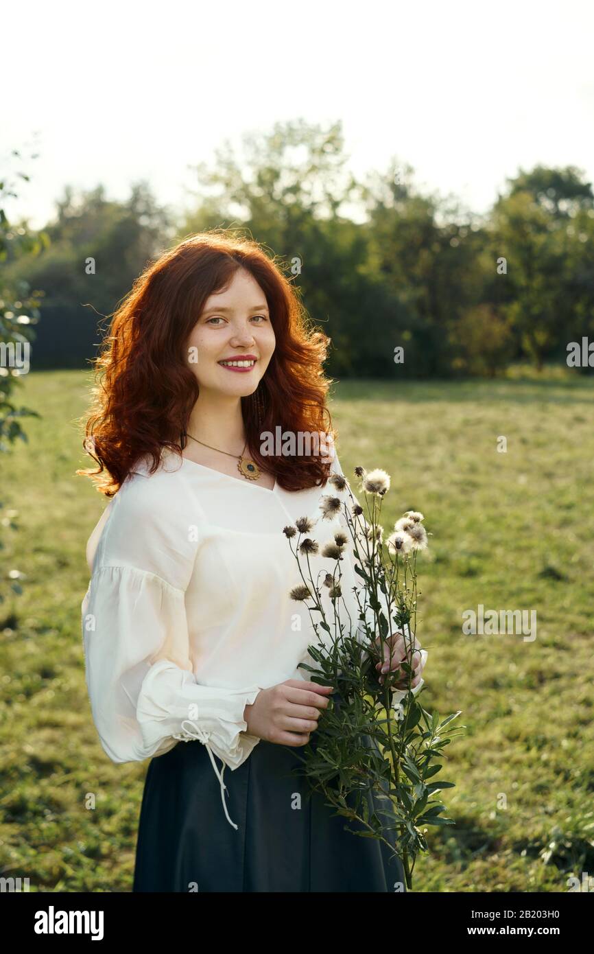 Beautiful young woman with red curly hair and freckles on her face. Stock Photo