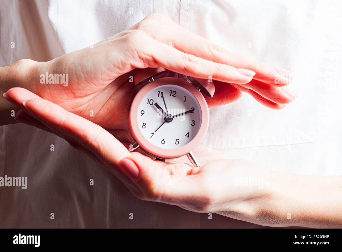 Hand holding small clock hi-res stock photography and images - Alamy
