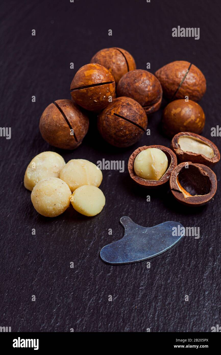 Organic macadamia nuts on black slate background, closeup. Stock Photo