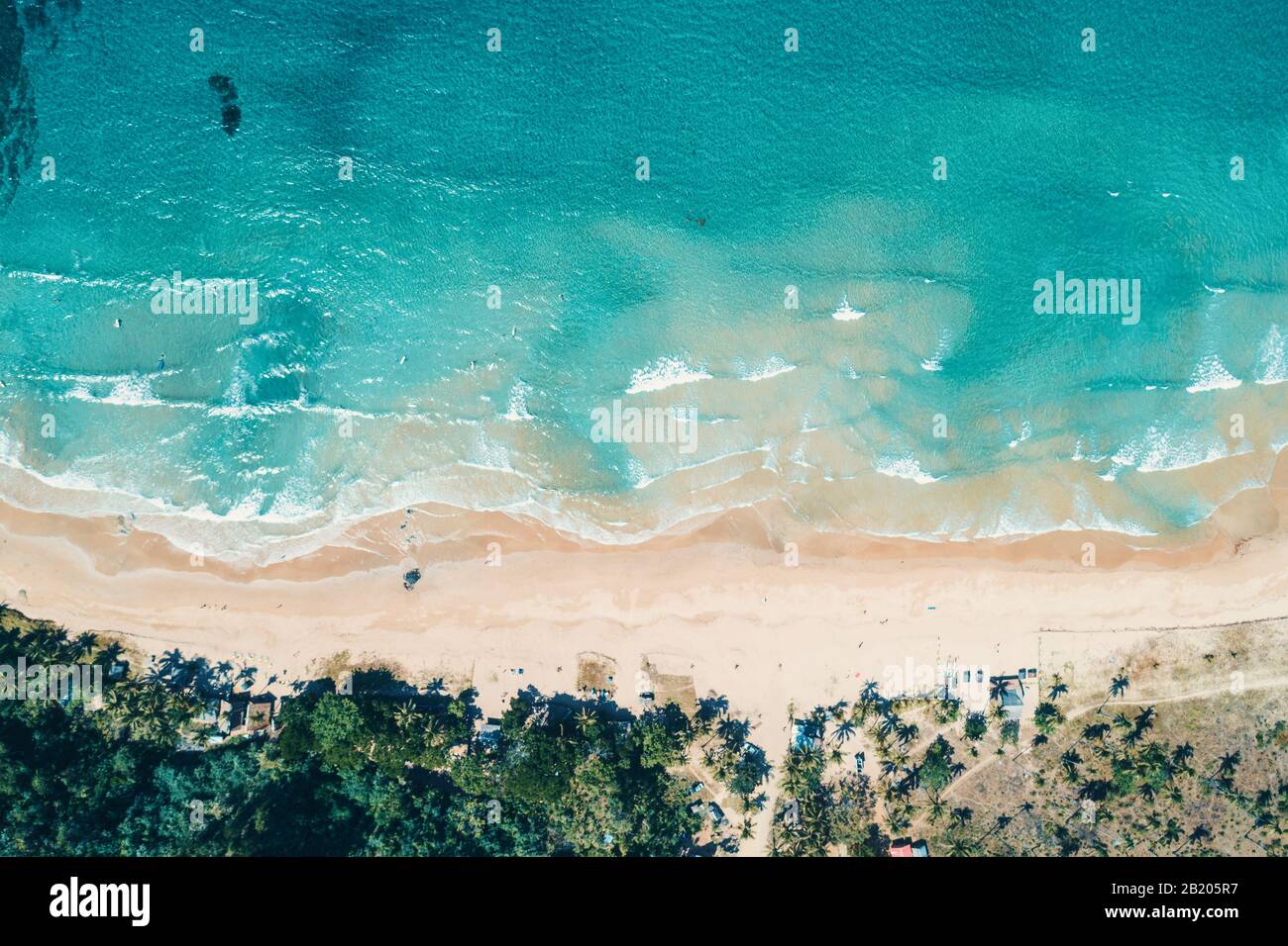 Aerial view to tropical sandy beach and blue ocean. Top view of ocean waves reaching shore on sunny day. Palawan, Philippines. Stock Photo