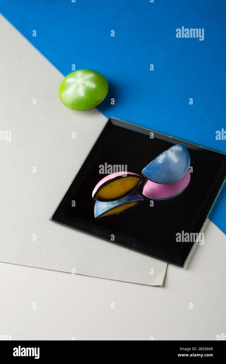 Chocolate candy on mirror and color paper, conceptual Stock Photo - Alamy