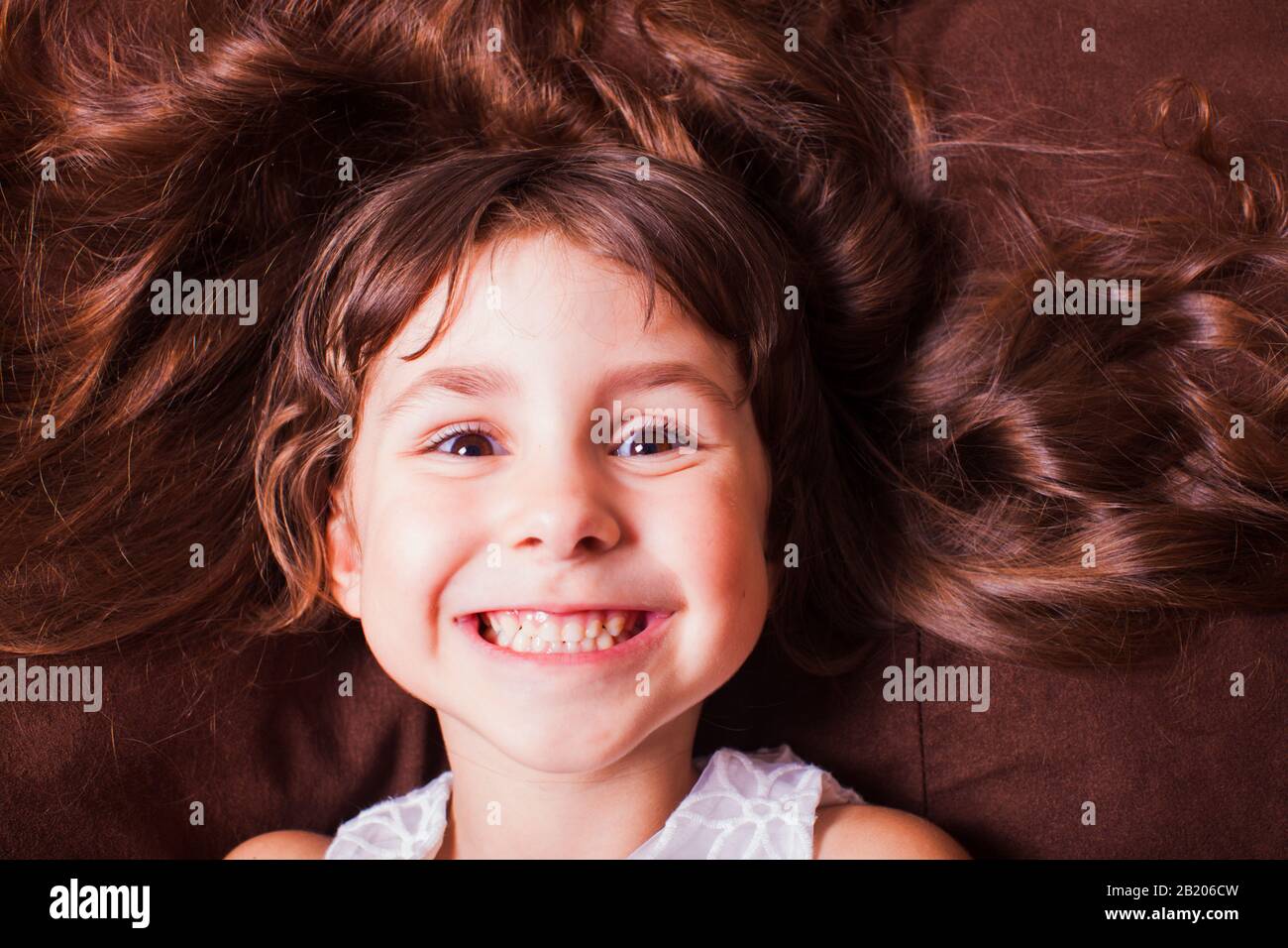 Dreamy charming little girl lying on a bed, top view. Face portrait