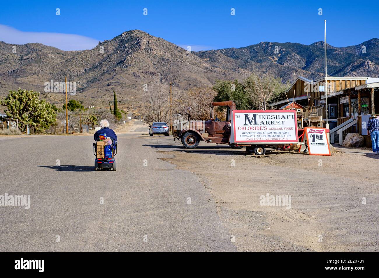 Mobility scooter driving in centre of desert road near store at Chloride, Arizona, 86431, USA. Stock Photo