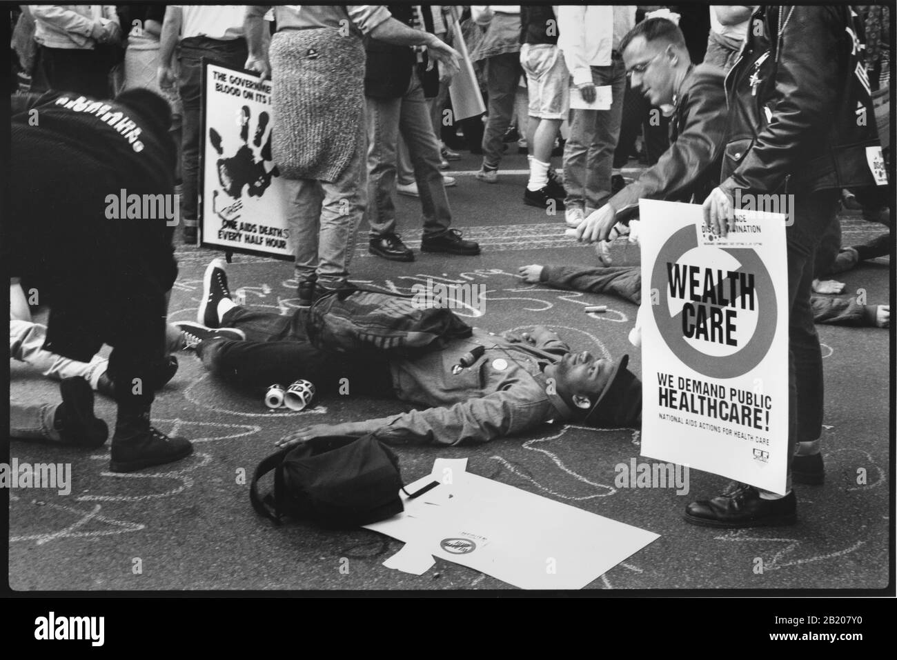 ACT UP National demonstration Chicago IL April 23 1990 - An activist from ACT UP performs a DIE IN (laying down in the street and allowing another activist to draw a chalk body outline to symbolise the people who have died of AIDS) during a protest outside of the American Medical Association. Protestors asked for a real health care system in the USA, more care for people with AIDS, more research money for people with AIDS, a reduction to the cost of coverage and an end to the ability of insurance companies to stop coverage when people were diagnosed with Acquired Immune Deficiency Syndrome. Stock Photo