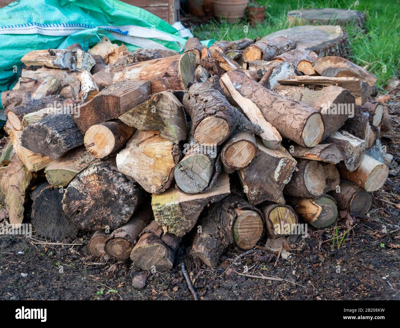 A pile of chopped wood logs in a garden  ready for burning on an open fire in the UK Stock Photo