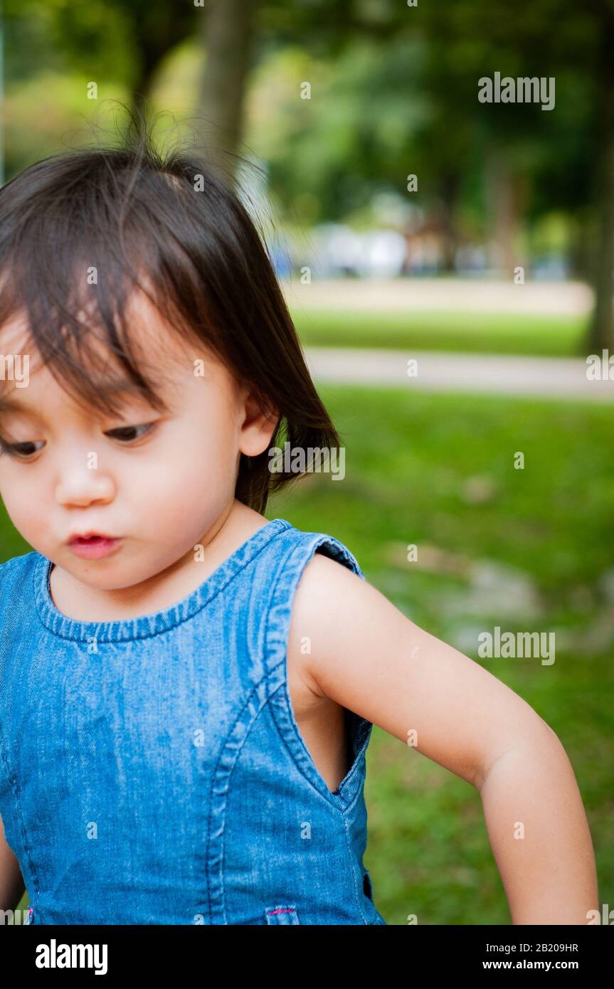 Asian 1 year old toddler is busy playing in a tropical park in the