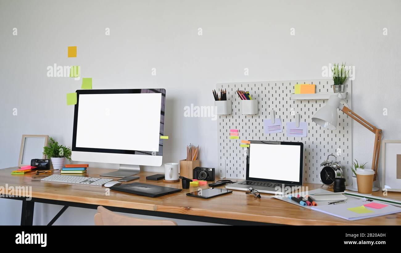 Photo of Graphic designer working table and graphic designing equipment putting on it. White blank screen laptop and Computer display leave space for Stock Photo
