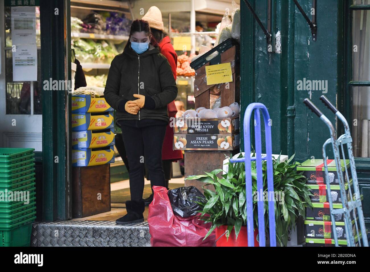 A shop worker wearing a face mask in China Town, Leicester Square, London, as the first case of coronavirus has been confirmed in Wales and two more were identified in England - bringing the total number in the UK to 19. Stock Photo