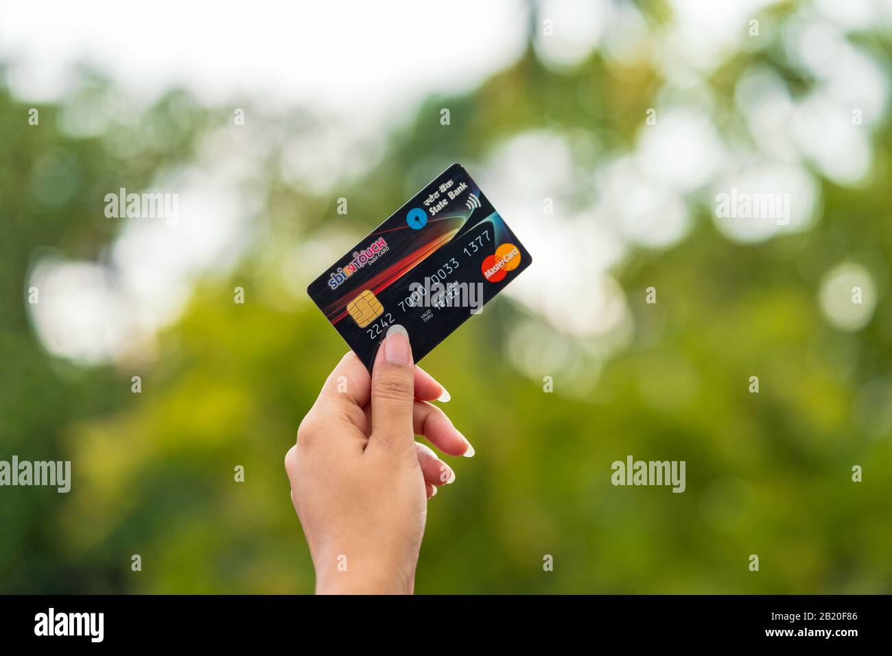 Young woman holding or showing State Bank of India's Credit or Debit card at outdoor background. Cocnept for SBI cards IPO, payment, finanace, Stock Photo