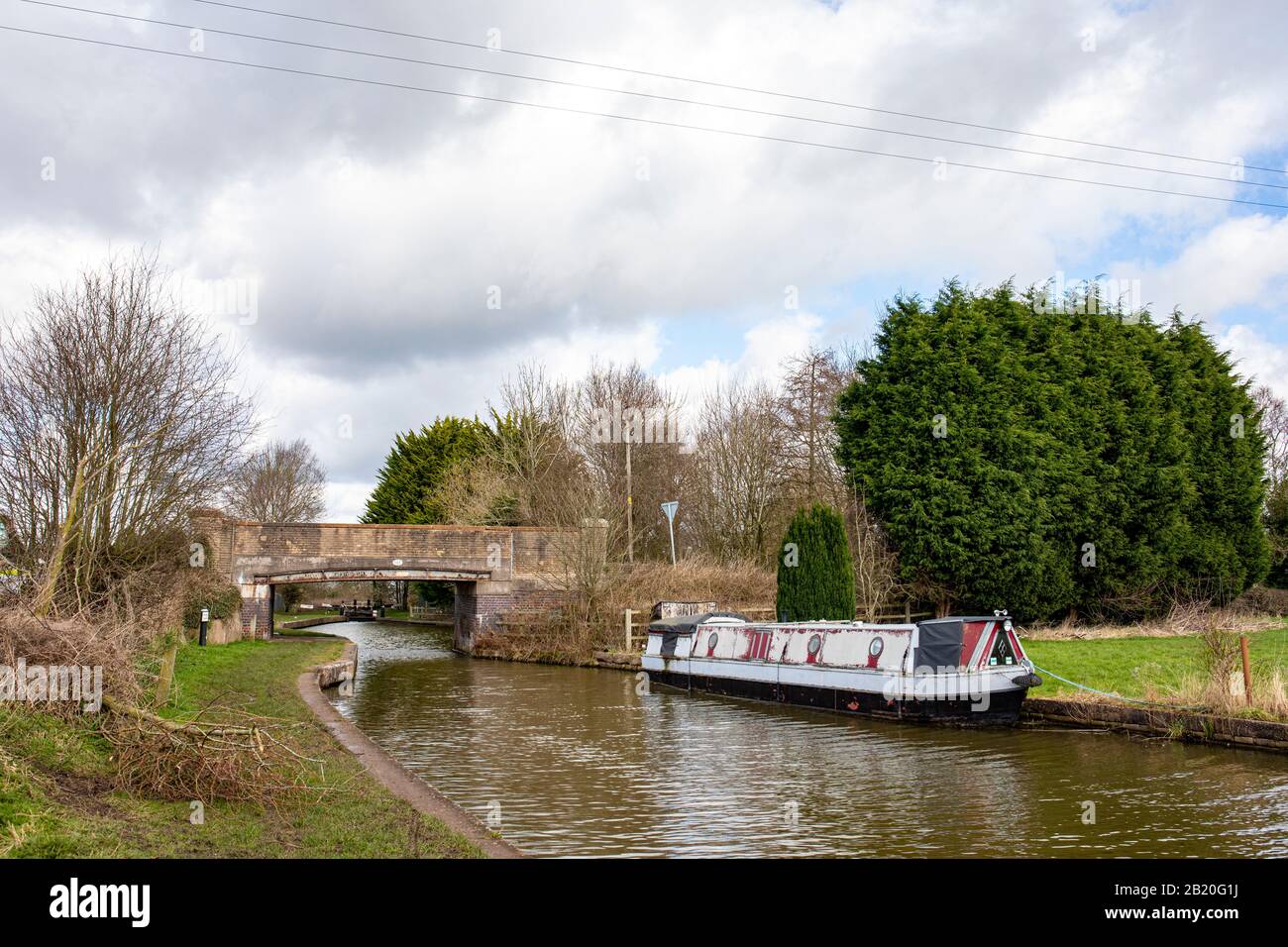 Narrow boat moored on the Trent and Mersey Canal with bridge 161 in distance, Cheshire UK Stock Photo