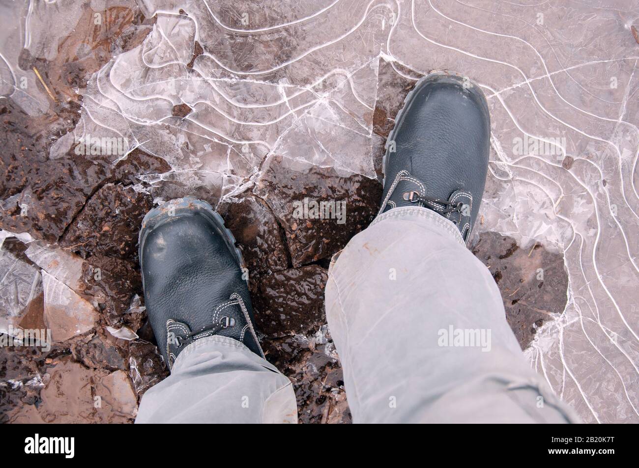 Black work boots on ice covered ground. Work shoes for work. Stock Photo