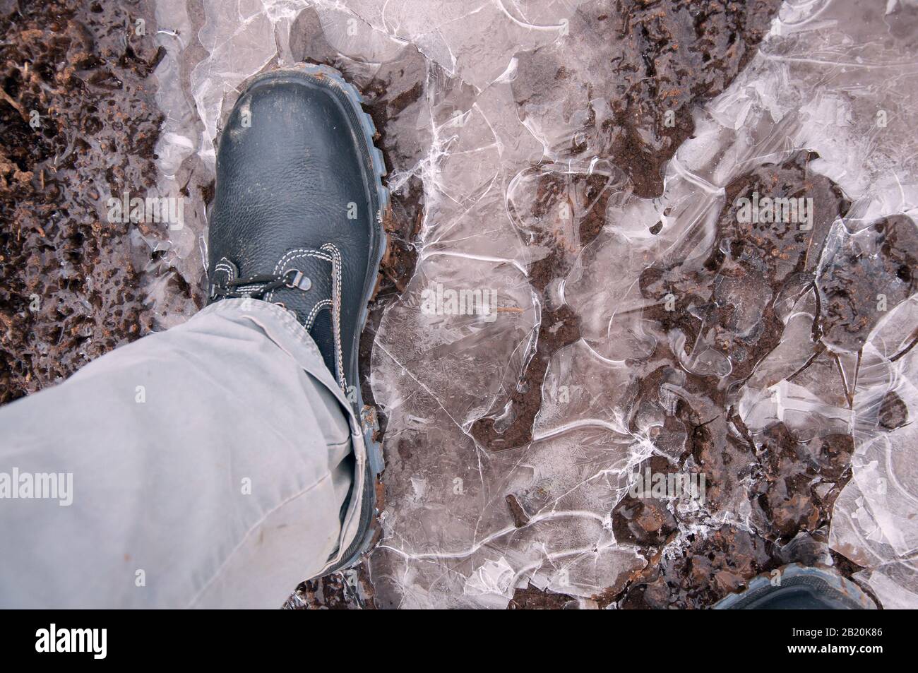 Black work boots on ice covered ground. Work shoes for work. Stock Photo