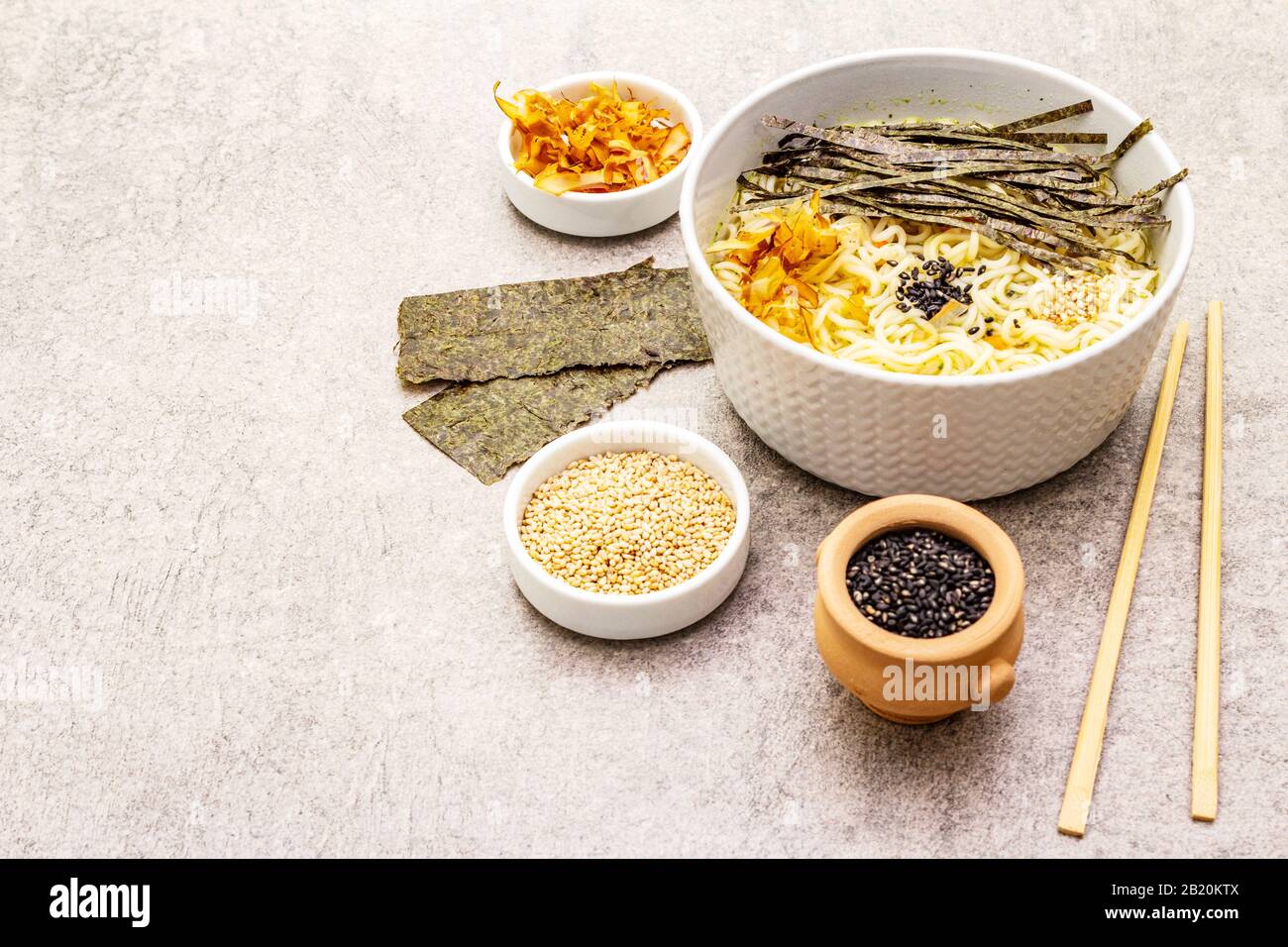 Noodles with seaweed, tuna flakes and sesame seeds. Healthy vegan (vegetarian) eating. In ceramic bowls, stone concrete background, copy space Stock Photo