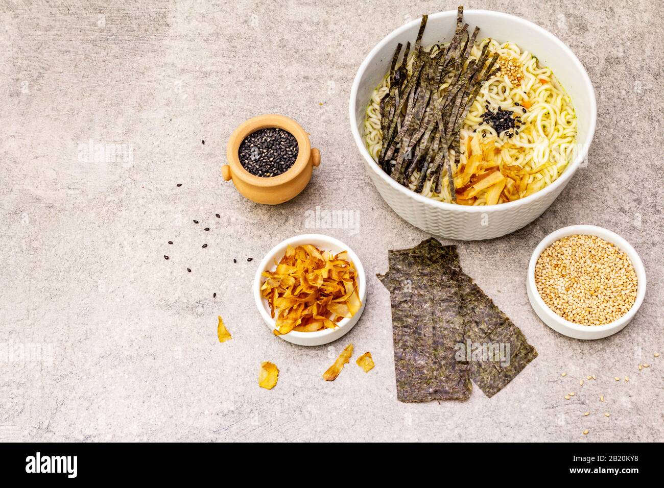 Noodles with seaweed, tuna flakes and sesame seeds. Healthy vegan (vegetarian) eating. In ceramic bowls, stone concrete background, copy space Stock Photo
