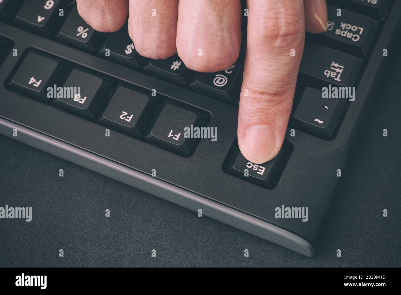 Person's finger pressing Escape key on a black computer keyboard. Close up. Stock Photo
