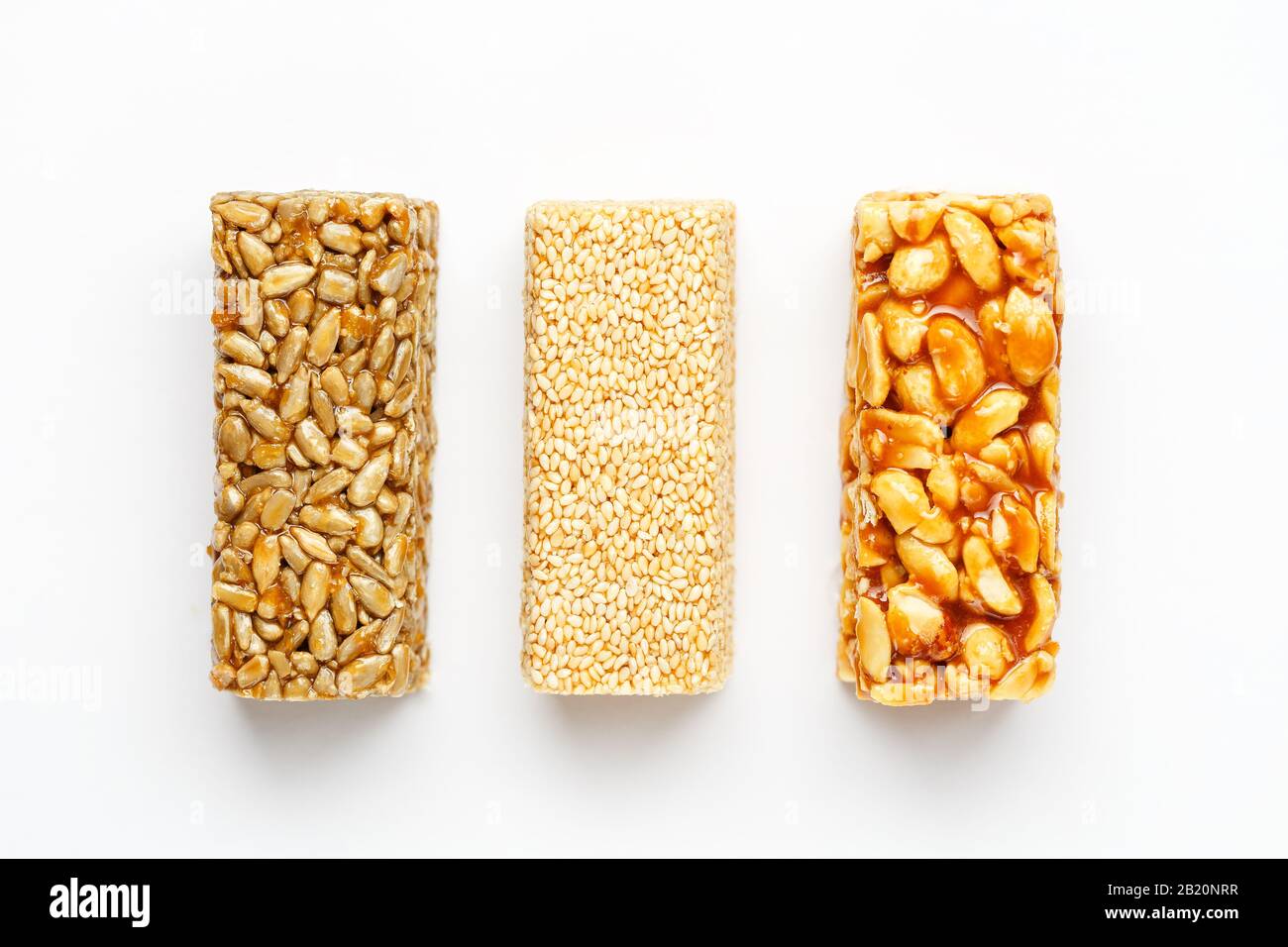 Grain granola bar with peanuts, sesame and seeds in a row on a white background. Top view Kozinaki Three assorted bars, isolate Stock Photo