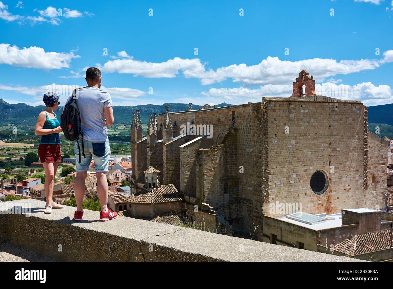 TARRAGONA, SPAIN - MAY 12, 2017: Couple standing before the romanic church of Saint Mary and amazing landscape of mountains in the medieval city of Mo Stock Photo