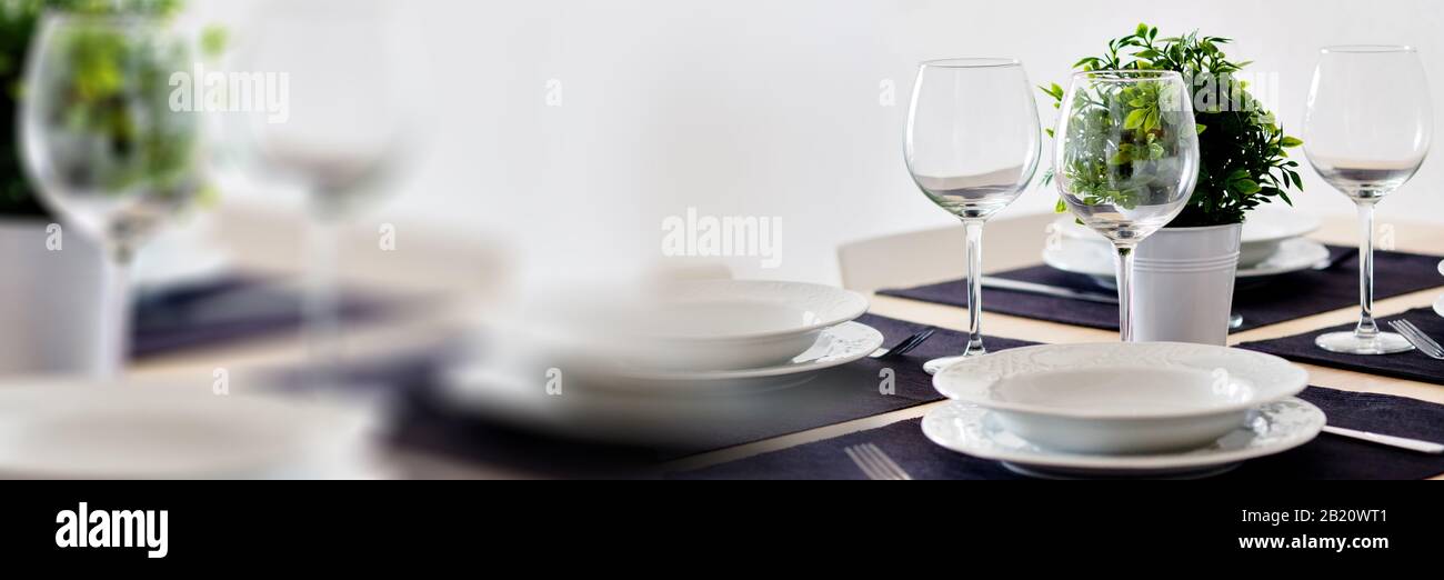 Close up view table setting served for dinner on violet place mats empty wine glasses plates flatware, no people. Horizontal image with copy space Stock Photo