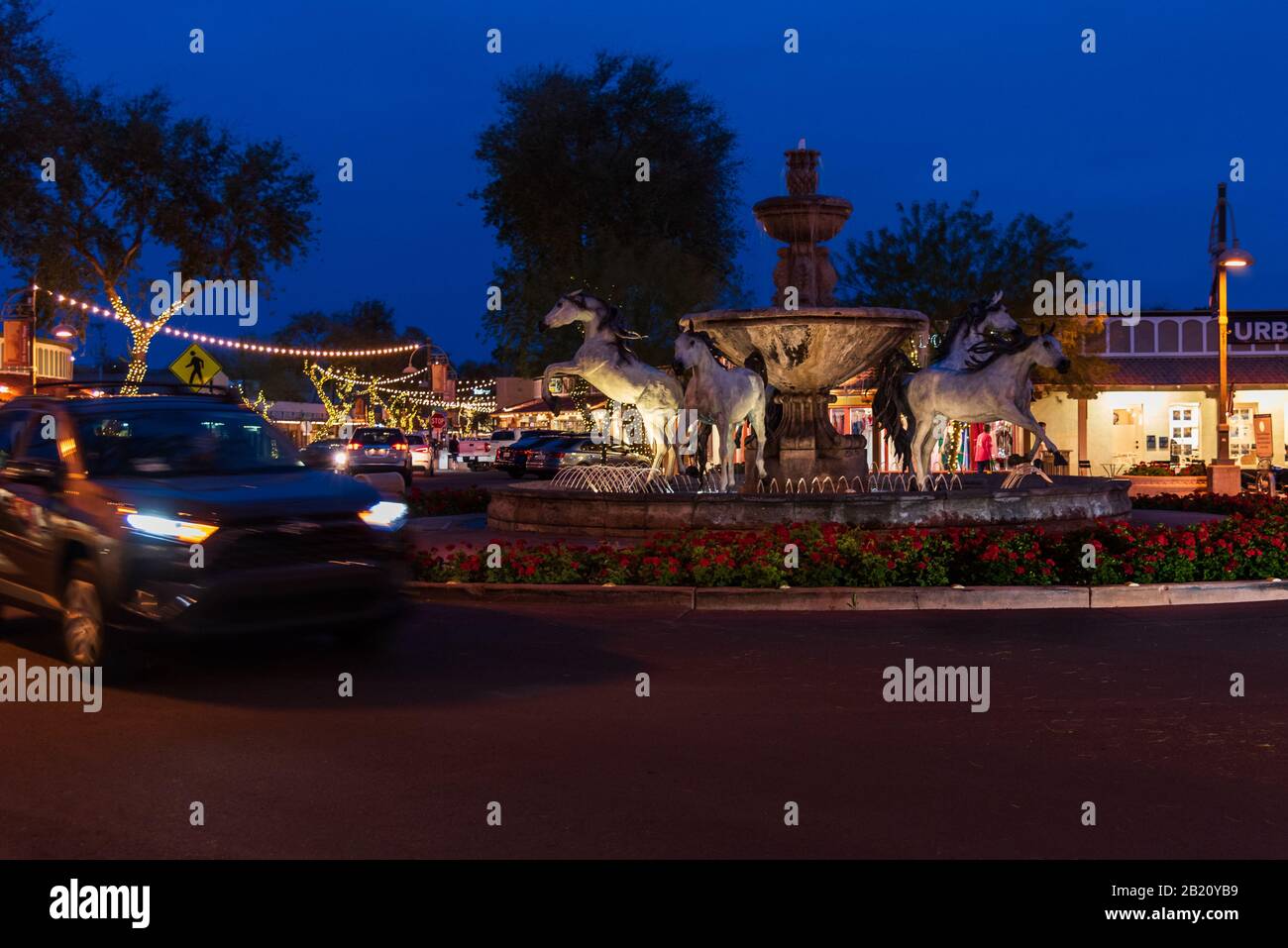 Cars driving by the bronze horse fountain on 5th Avenue in Old Town Scottsdale, Arizona. Stock Photo