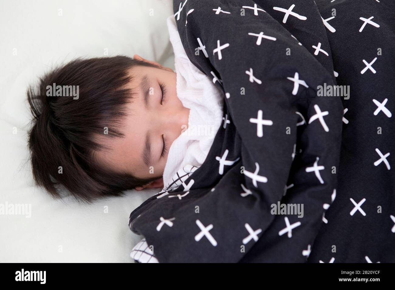 sleeping boy covered with blanket in bed Stock Photo