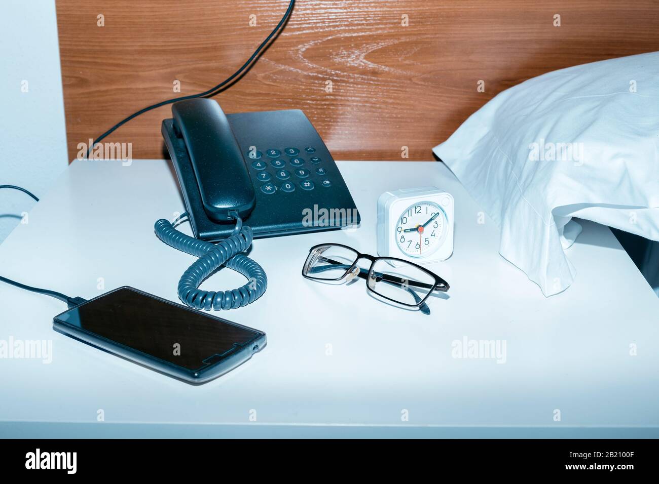 old and new technology of communication on a bedside table by the pillow Stock Photo