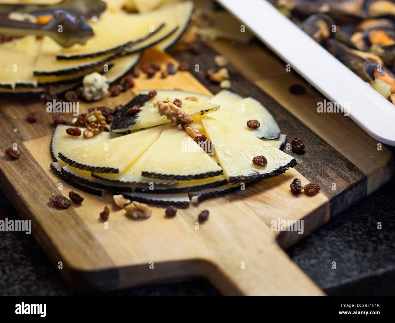 view of cured cheese cut into triangles on a wooden board and nuts Stock Photo