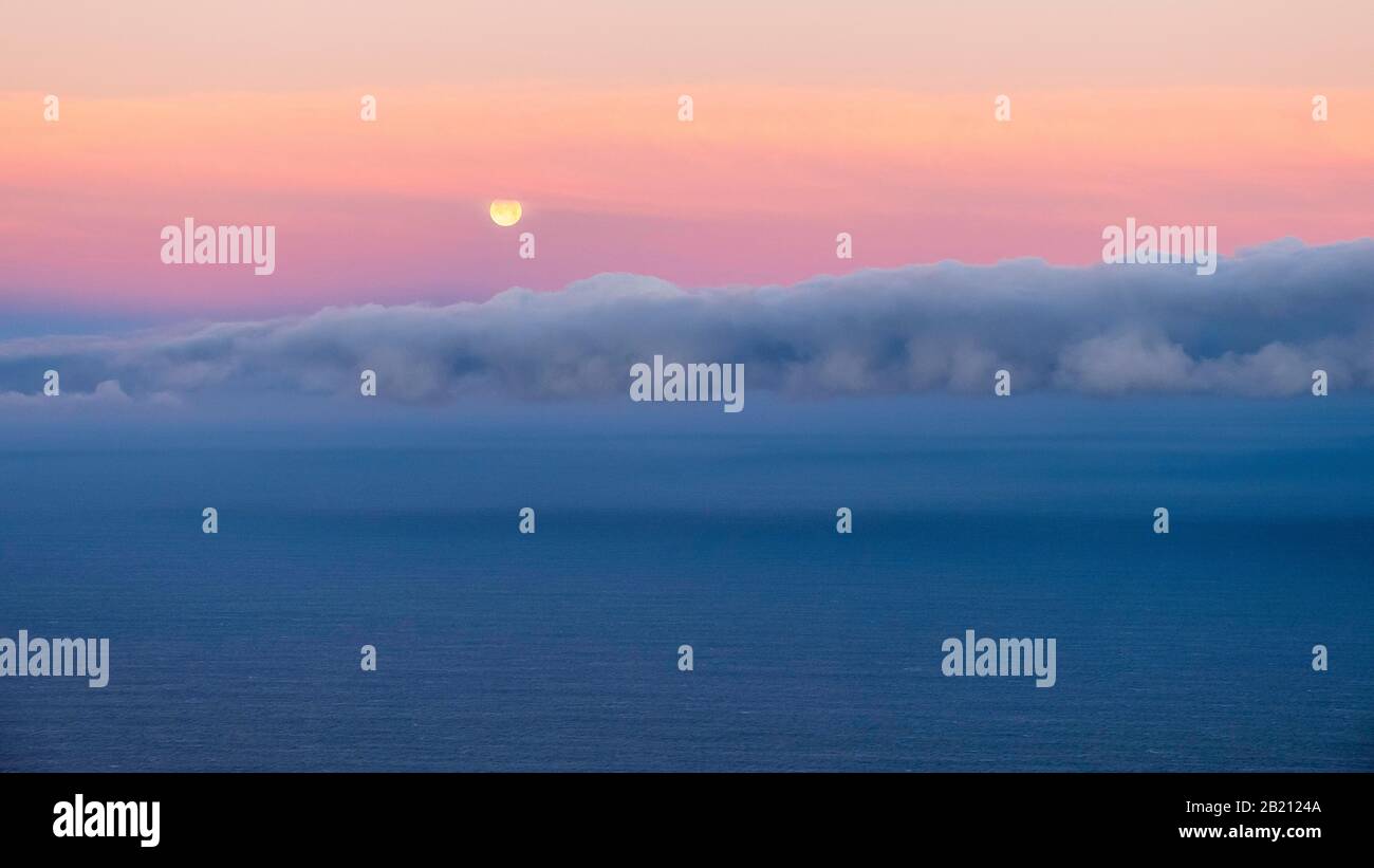 Moonset, sunrise mood at the sea, clouds in the sky, Spain Stock Photo