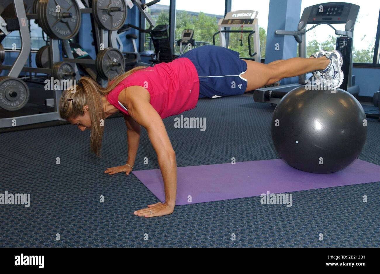 Austin, Texas  Woman in her late 20s works out on a floor mat with exercise ball  at a modern gym.  MR September 2004  ©Bob Daemmrich Stock Photo