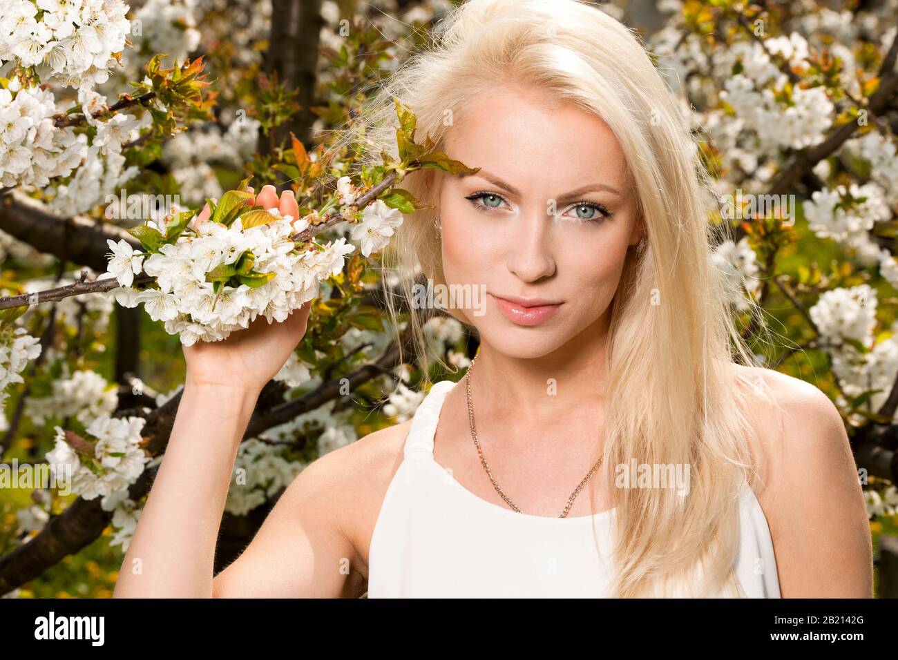 Beautiful young woman on cherry plantation in spring cherry blossom