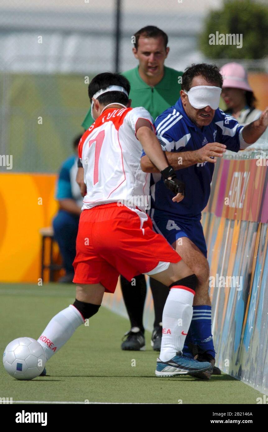 Korea (white and red) vs. Greece at the 5-a-side football competition at the Athens Paralympics. Left to right, #7 is Jong Suk Yoon of Korea and unidentified Greece player. ©Bob Daemmrich Stock Photo
