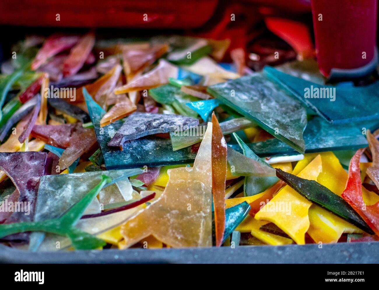 Shards of colorful pieces of stained glass sit in a pile at a glass art work shop Stock Photo