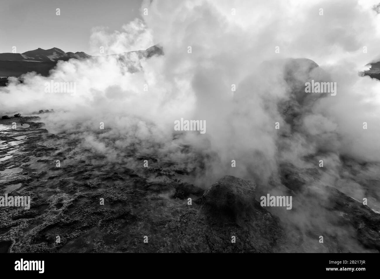 A geyser steams at sunrise, El Tatio Geyser Field, Andes Mountains, Altiplano, Atacama Desert, Antofagasta region, Chile, black and white Stock Photo