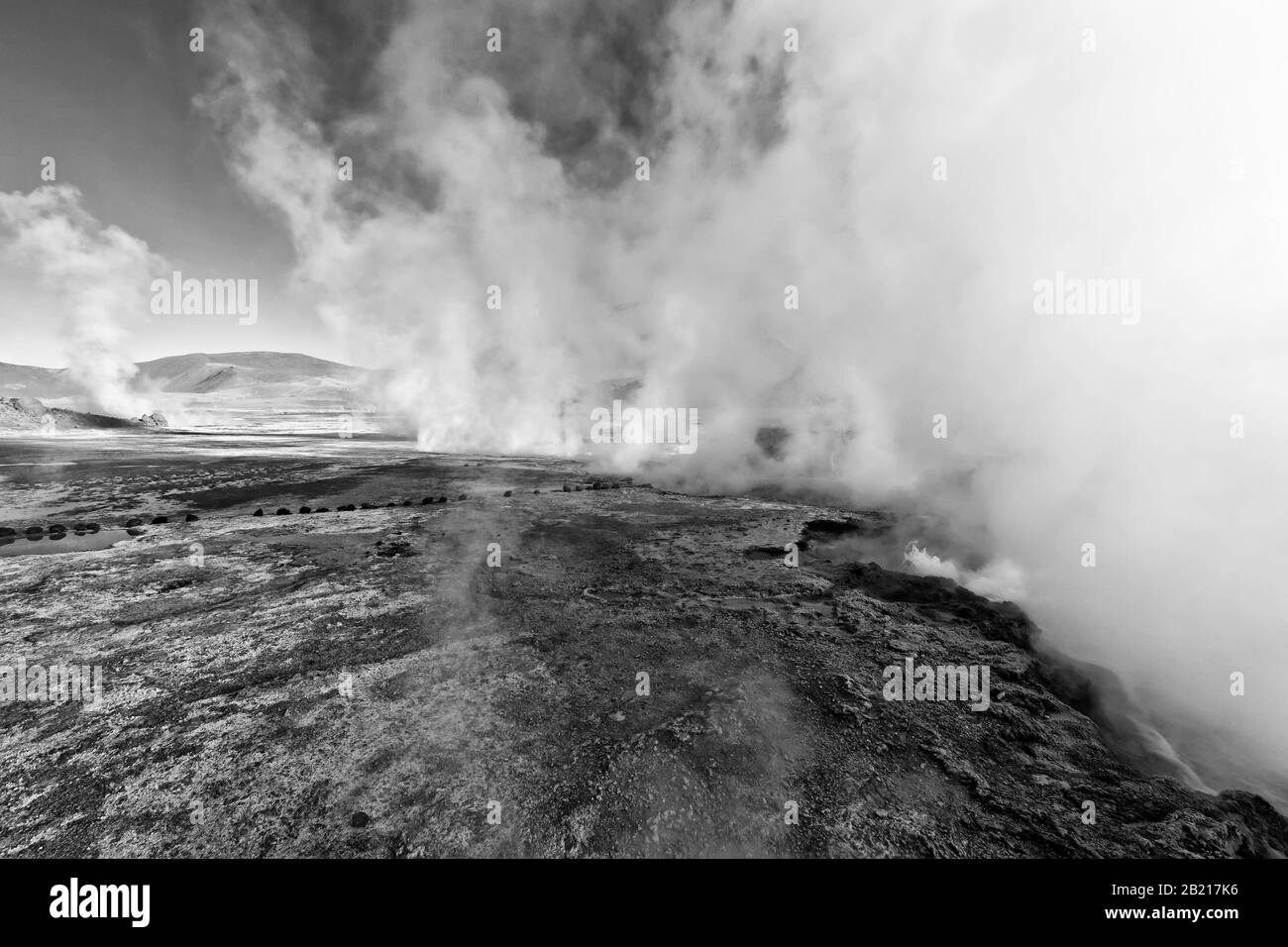 A line of geysers emit steam at sunrise, El Tatio Geyser Field, Andes Mountains, Altiplano, Atacama Desert, Antofagasta, Chile, black and white Stock Photo