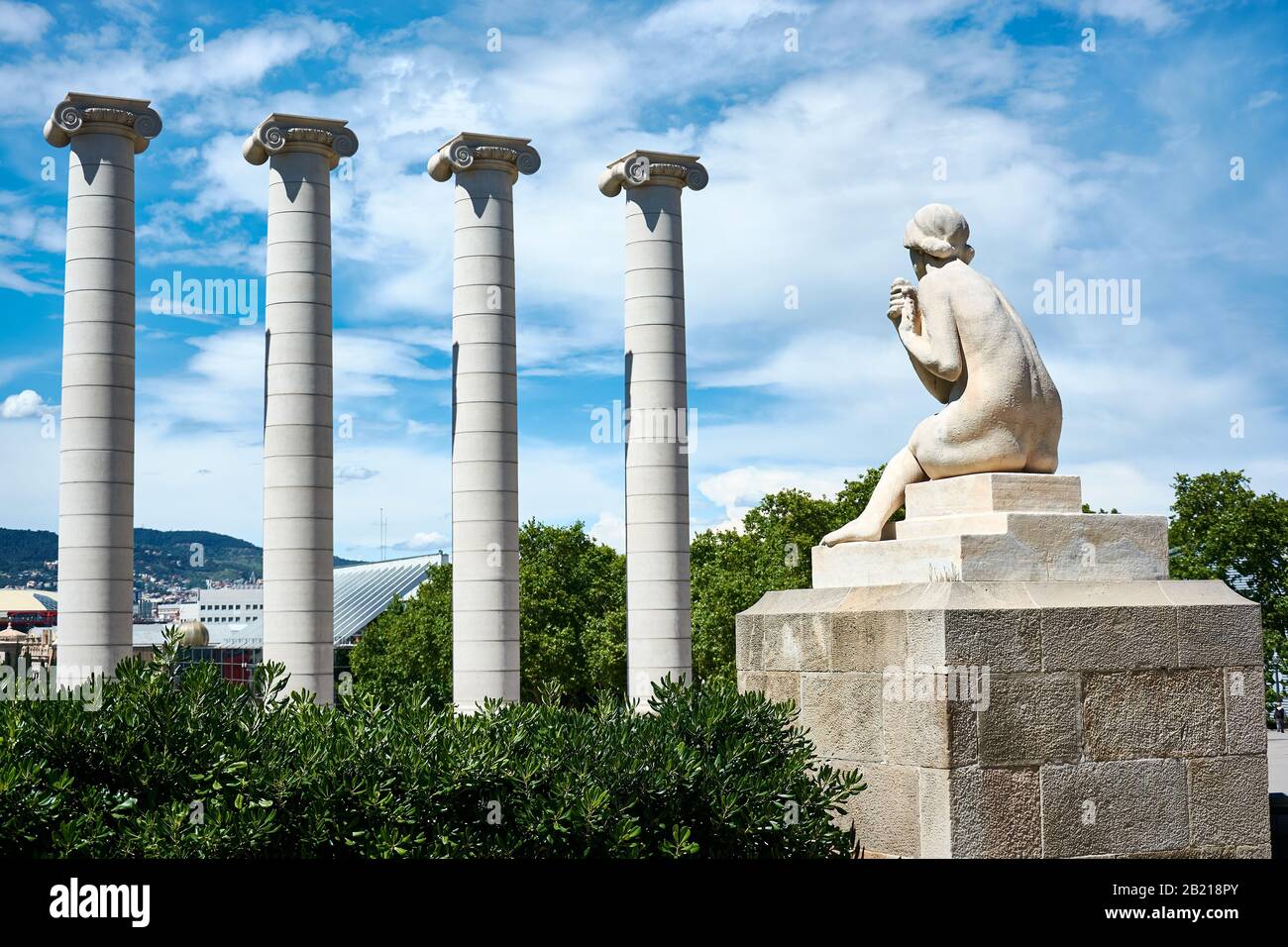 BARCELONA, SPAIN - MAY 13, 2017: Female sculpture and the iconic Four Columns on Montjuic hill in the center of the city. Stock Photo