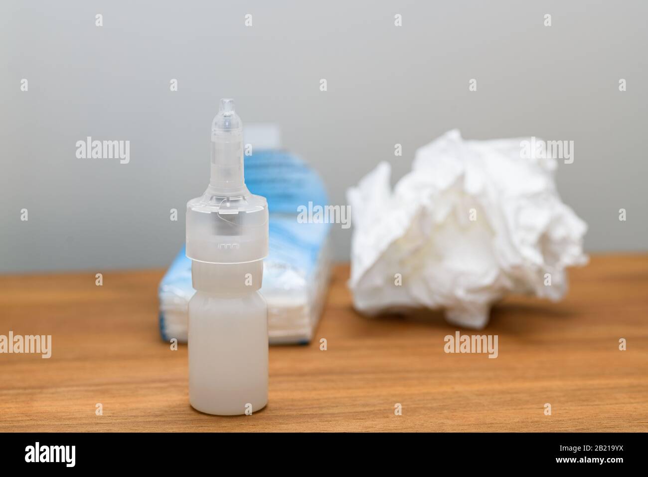 Nasal spray bottle and paper tissue on a nightstand used during cold, flu or virus.Concept for medical conditions at home. Stock Photo