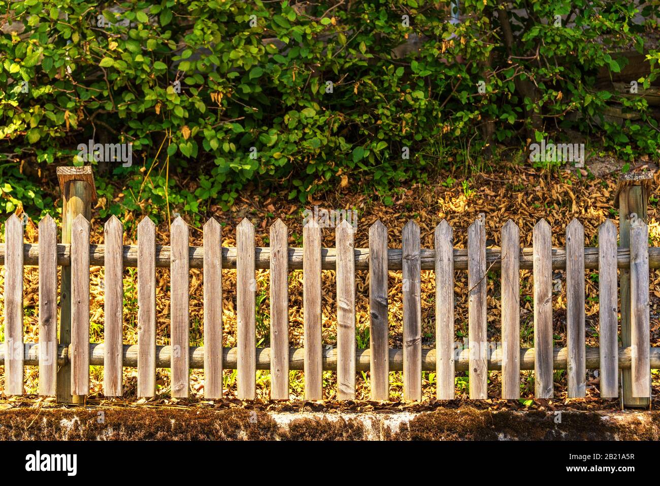 A low, wooden fence standing on a concrete wall, illuminated by the ...