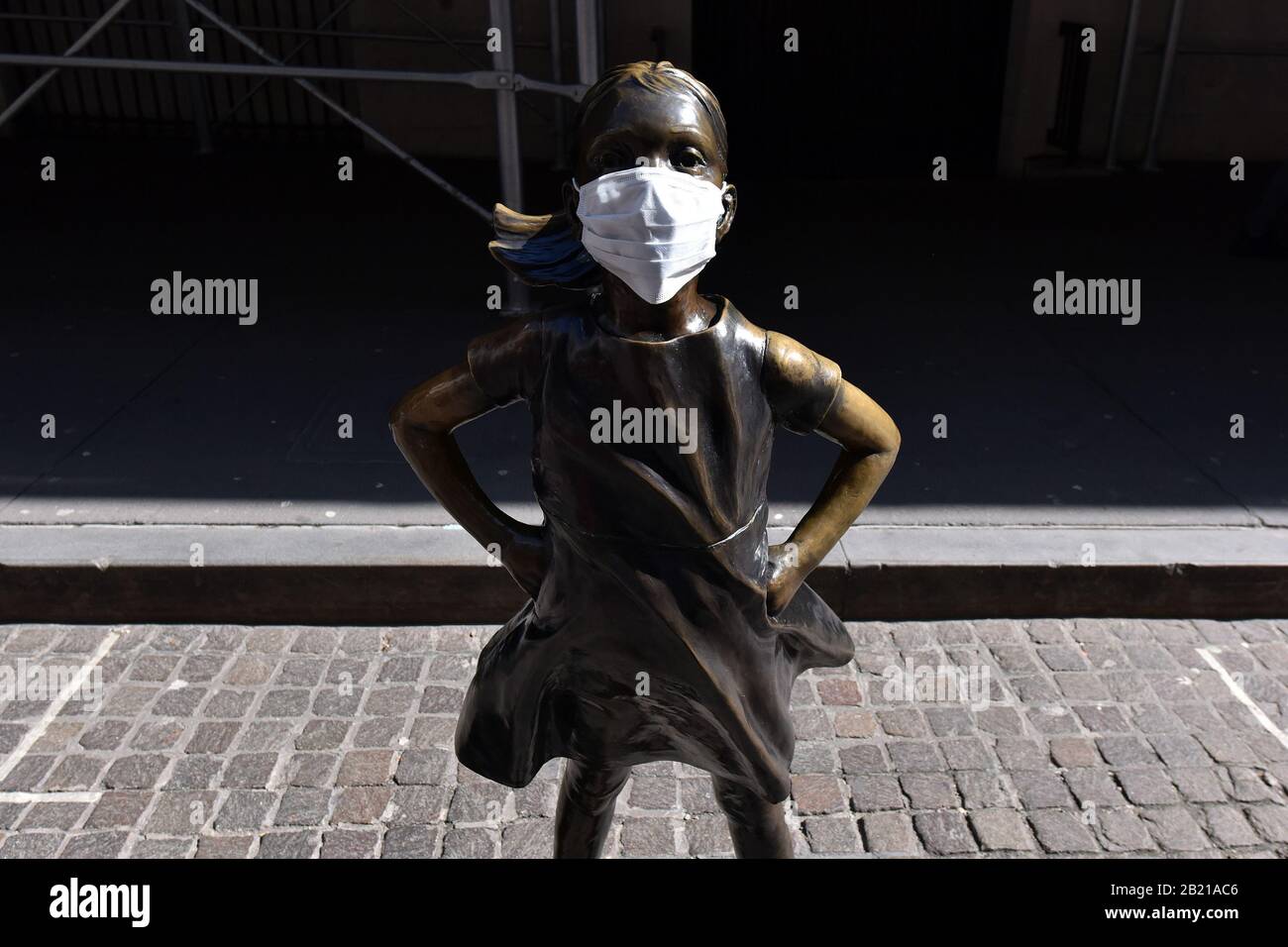 New York City, USA. 28th Feb, 2020. A photo illustration of The Fearless Girl statue by Kristen Visbal wearing an anti-viral face mask outside the New York Stock Exchange on Feb. 28, 2020. The DOW dropped over 1000 points during early trading Friday morning over concers of the effects of the Corona virus. (Photo by Anthony Behar/Sipa USA)( Credit: Sipa USA/Alamy Live News Stock Photo