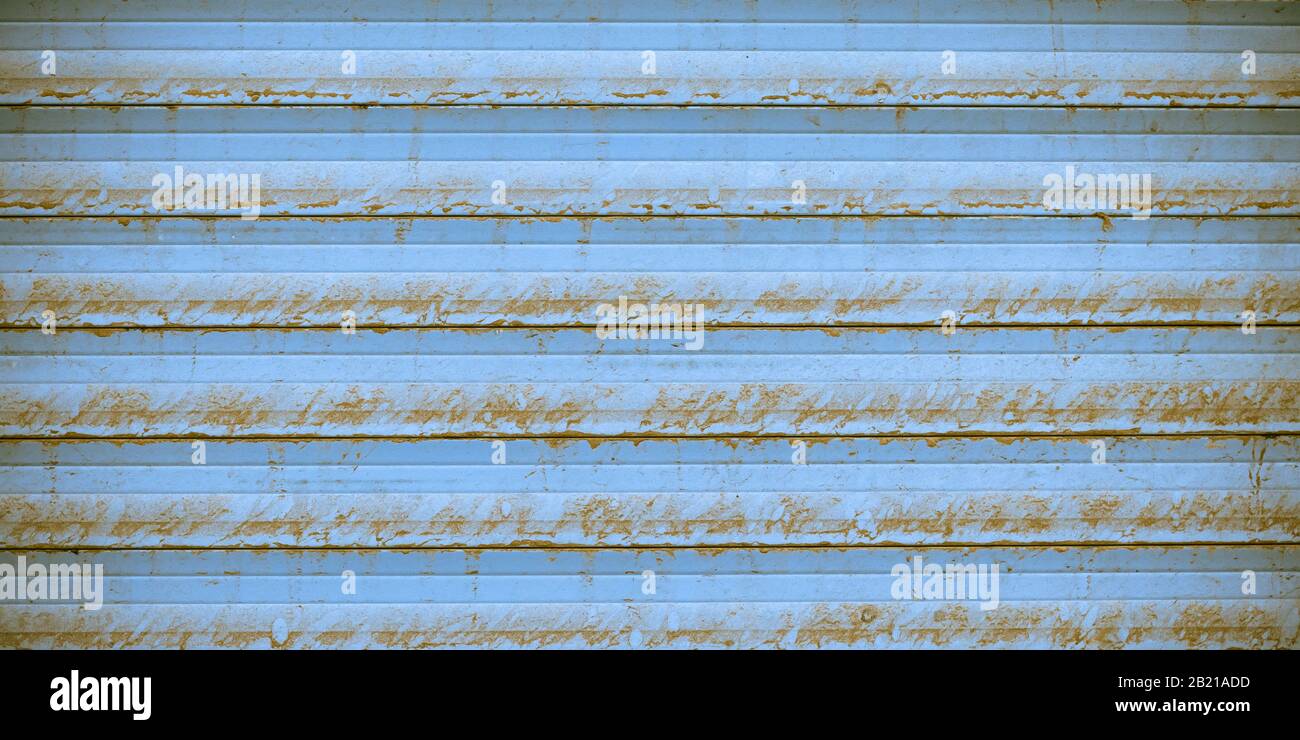 Rusty metal striped surface of jalousie, blue metallic ribbed fence, striated wall texture. Urban grunge background with straight lines. Exterior elem Stock Photo