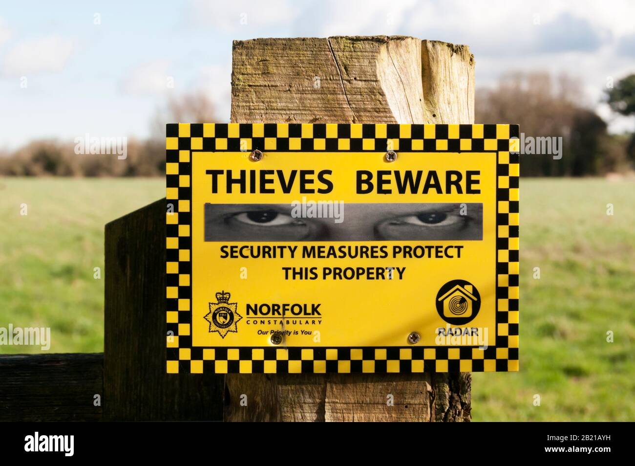A Norfolk Constabulary sign reads Thieves Beware Security Measures Protect this Property on a country fence post. Stock Photo