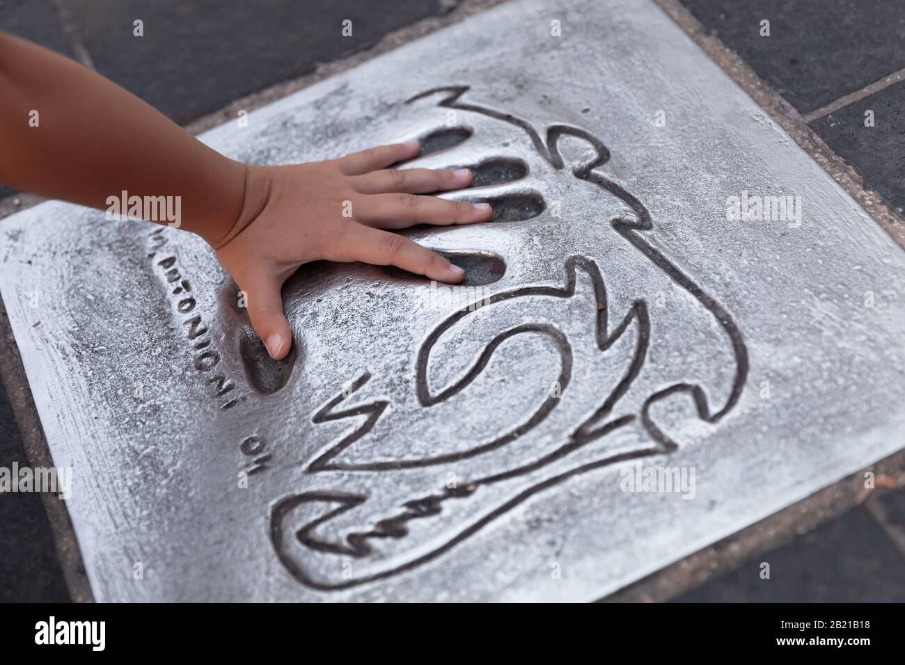 Cannes, France - August 14, 2018: Child puts his hand over Michelangelo Antonioni hand print at Avenue of Stars. Star-Studded Floor of Cannes Stock Photo