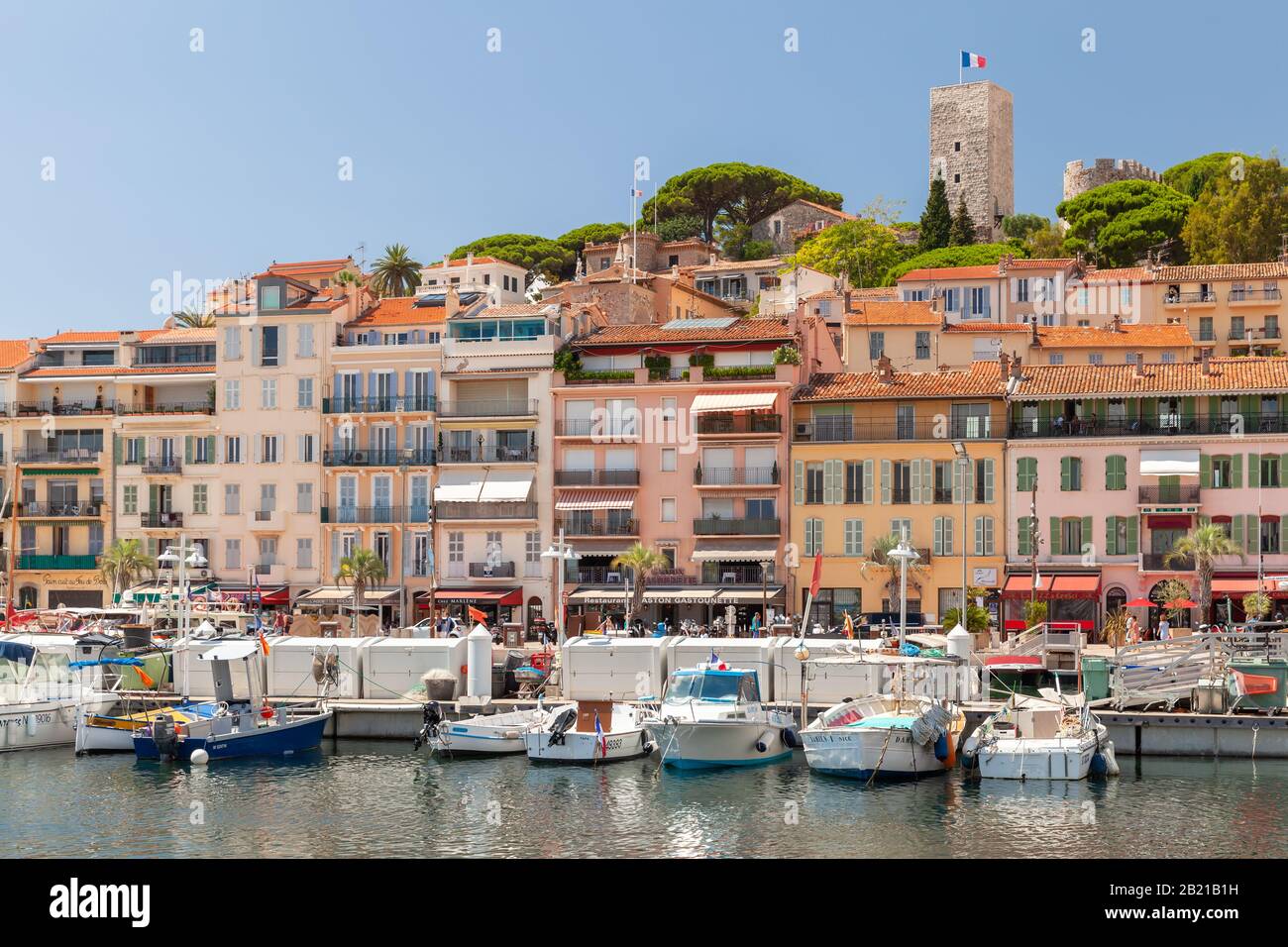 Cannes, France - August 14, 2018: Coastal view of Cannes at sunny summer day, people walk the street near old port with moored boats Stock Photo