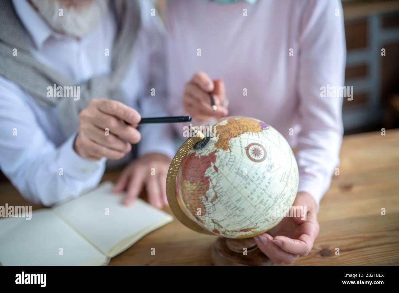 Couple of pensioners spinning the old globe Stock Photo
