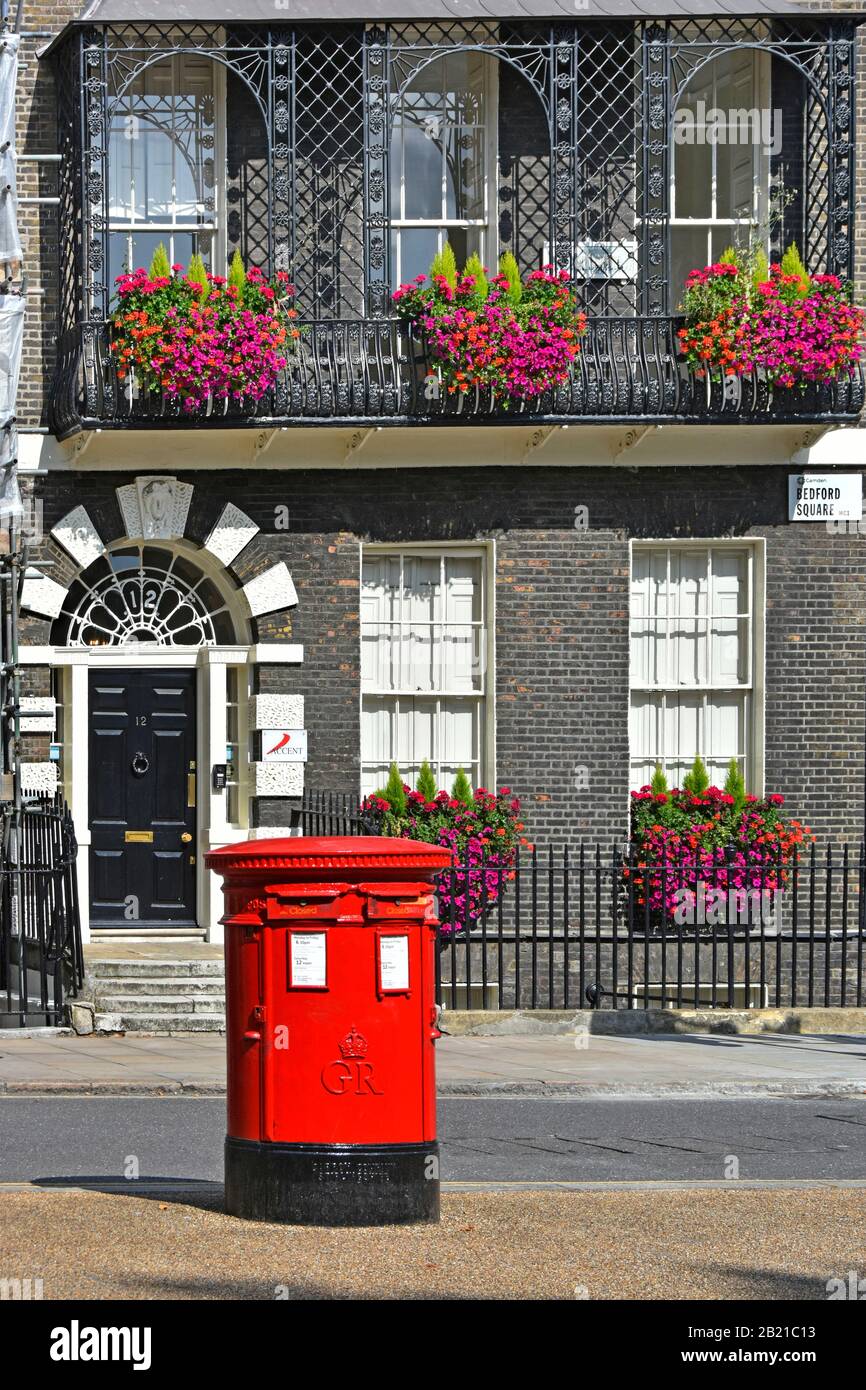 Double Royal Mail red GR pillar post box & closed plates on slots located at Bedford Square Georgian property & window box balcony flowers London UK Stock Photo