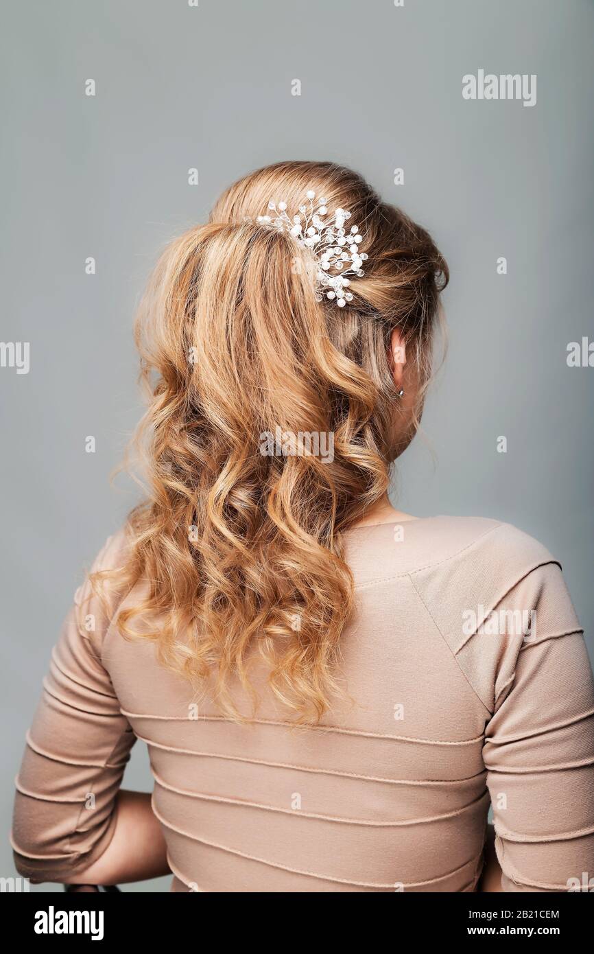 Wave curls hairstyle. Hairstyle on blond hair woman with long hair on a white background. Professional hairdressing services.Hair styling, making Stock Photo