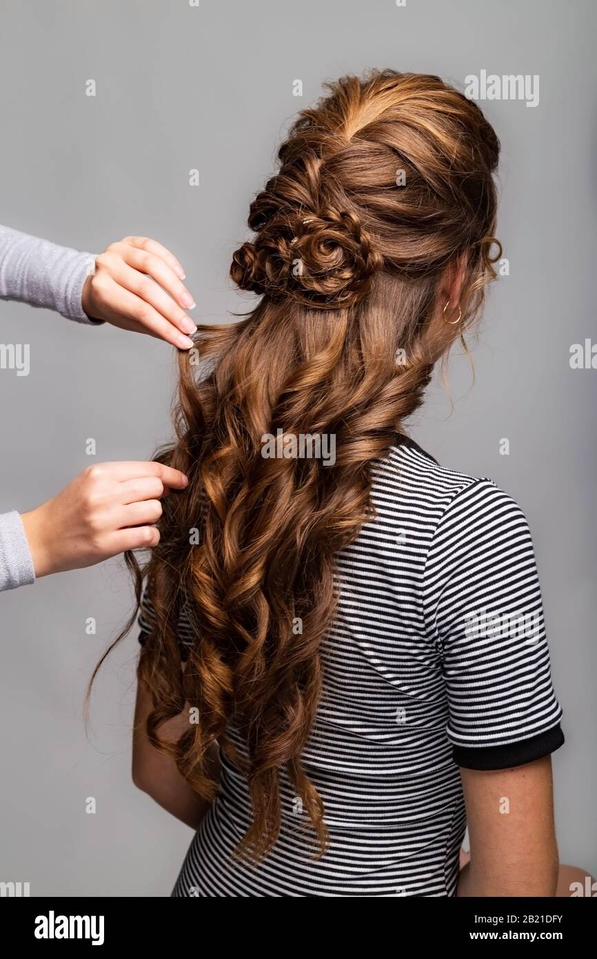 Wave curls hairstyle. Hairdresser making hairstyle to red brown hair woman  with long hair using comb on gray background. Professional hairdressing  Stock Photo - Alamy